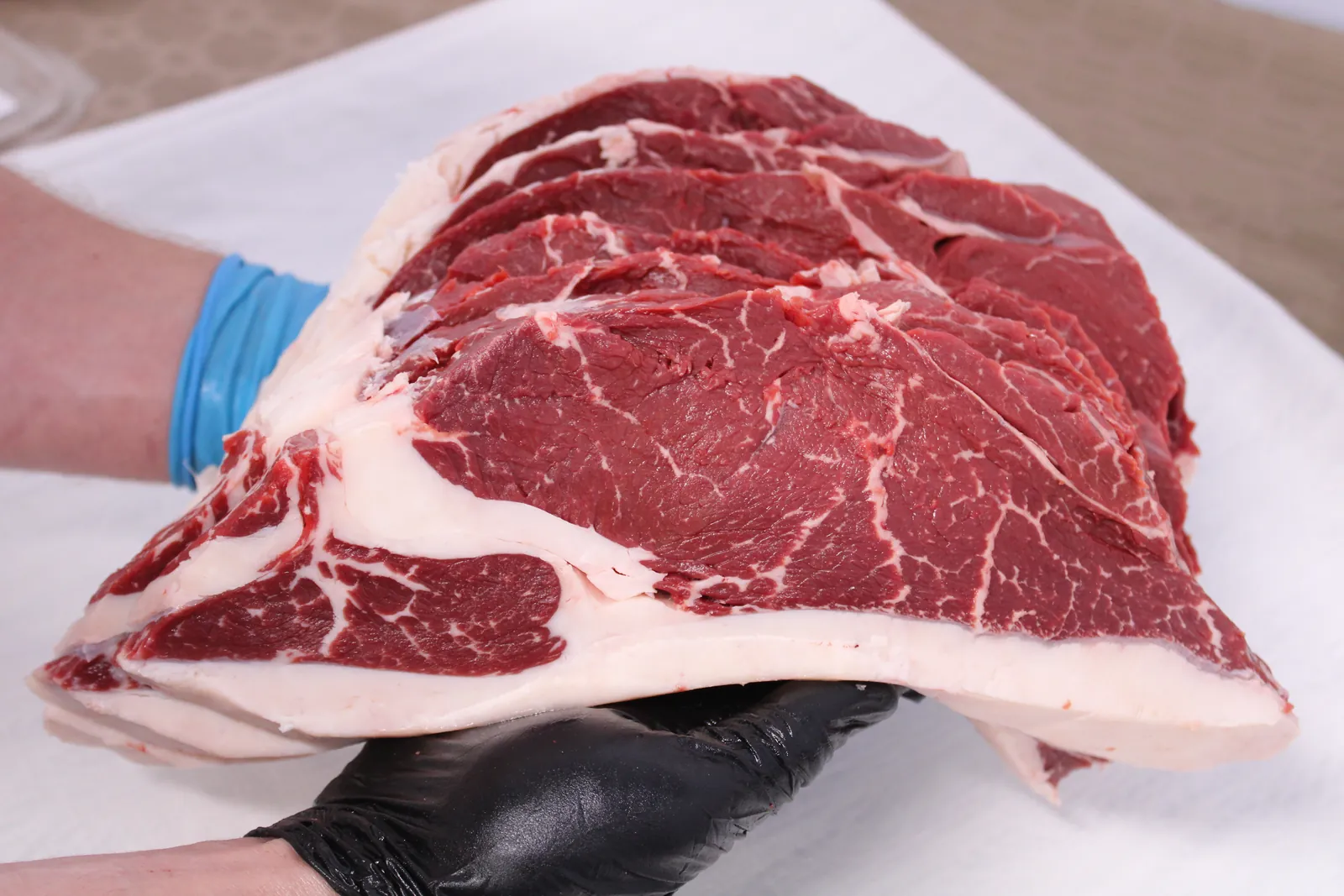 A butcher holding a freshly cut ribeye
